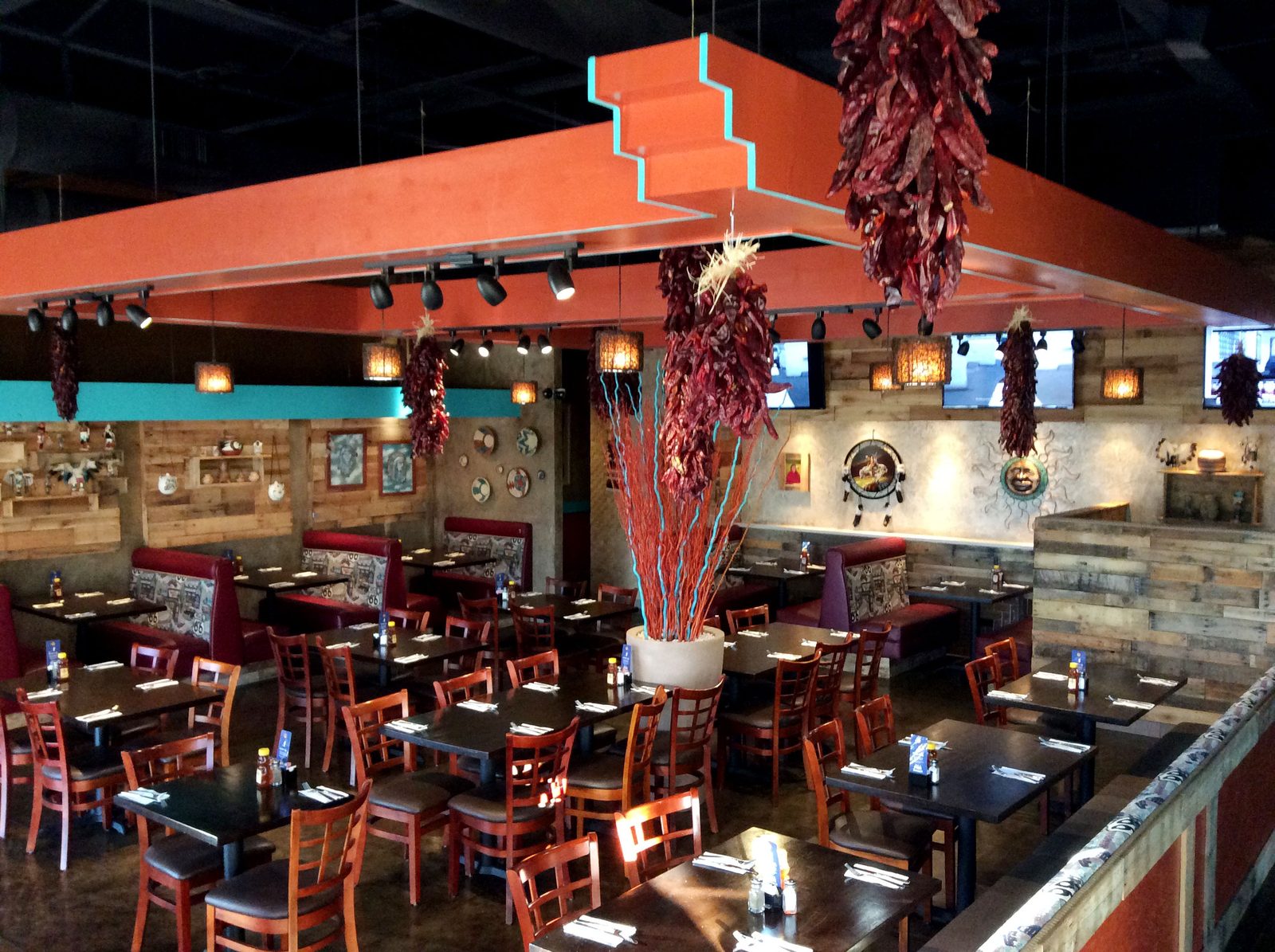 The dining room: red booths, dark wood tables, strings of dried red chiles hanging from an orange and turquoise ceiling, pottery and folk art on the walls